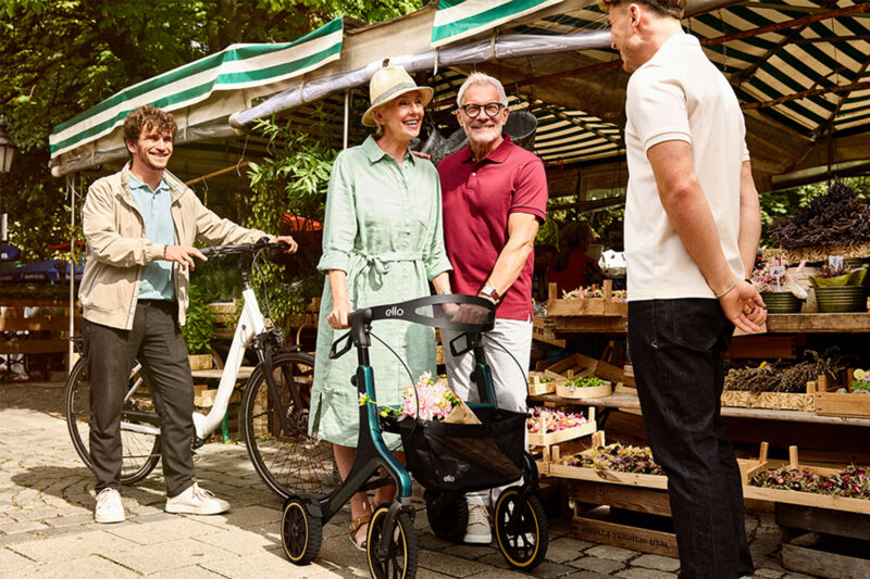 Älteres Paar mit Rollator kauft auf dem Markt ein